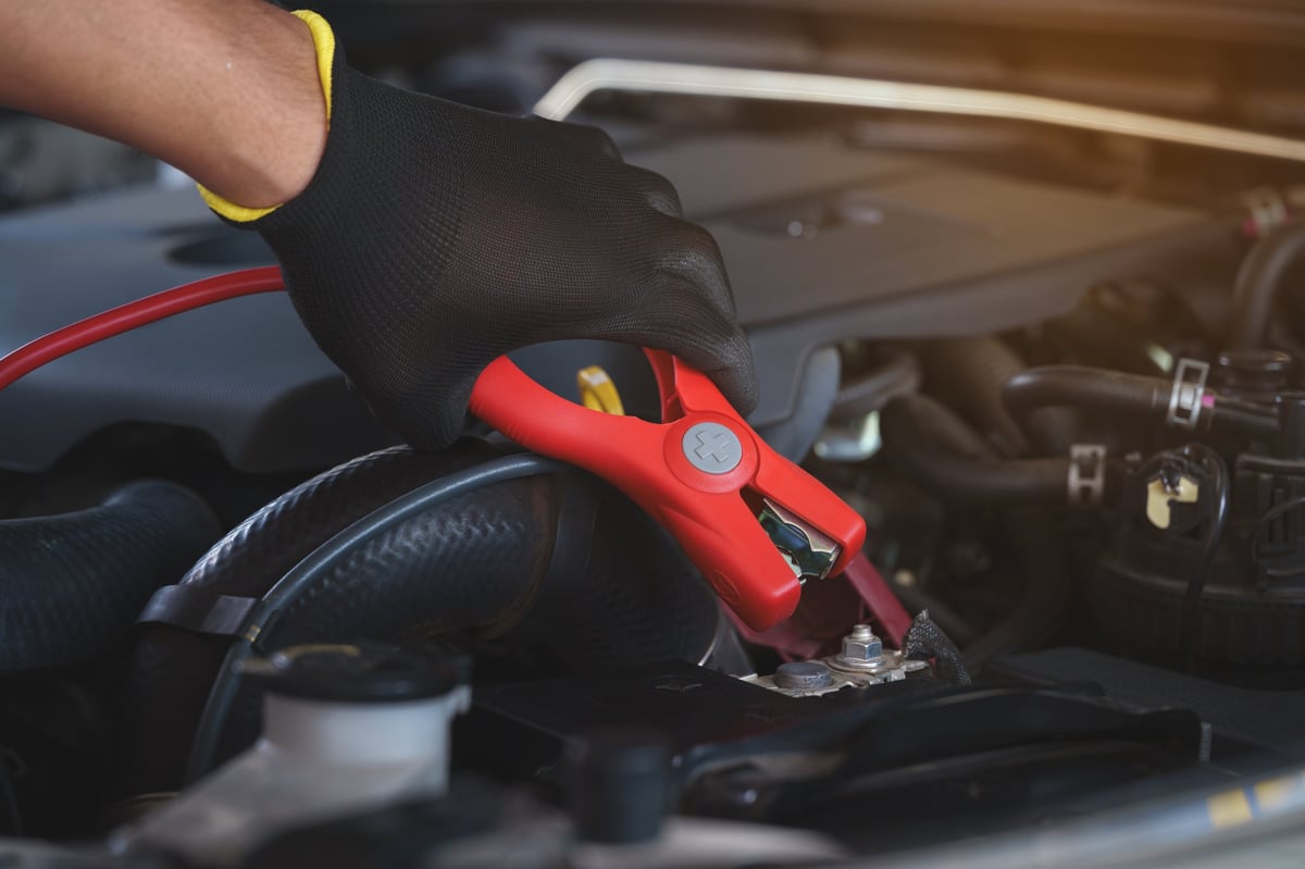 Technician jump starting a car battery with jumper cables